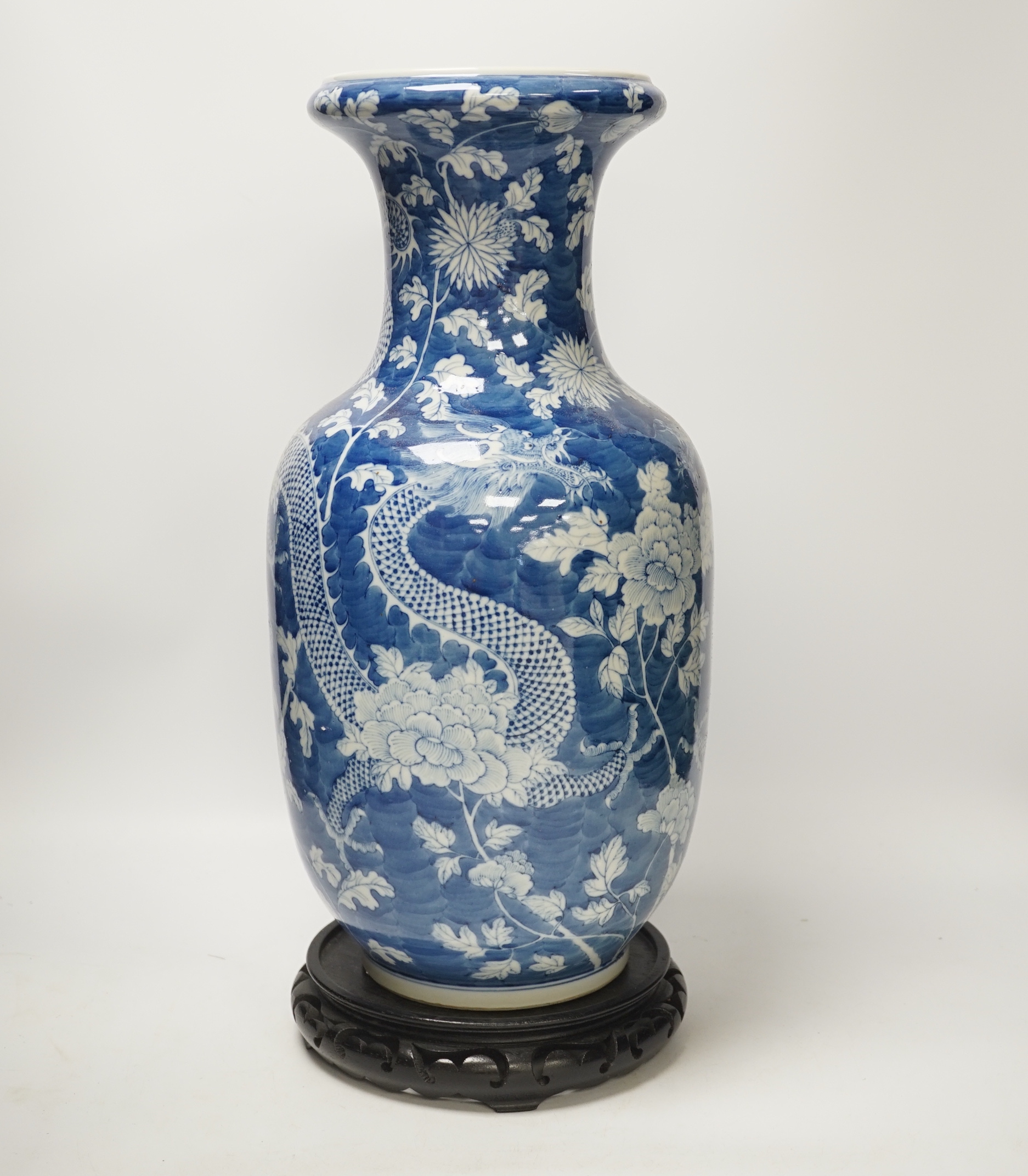 A Chinese blue and white baluster vase decorated with dragons and flowers together with an unassociated carved hardwood stand, 44cm high